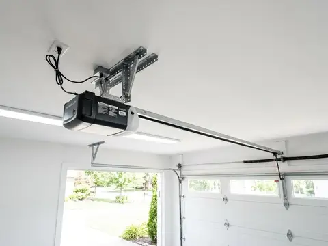 Newly mounted belt drive garage door opener and rail on a clean white garage ceiling